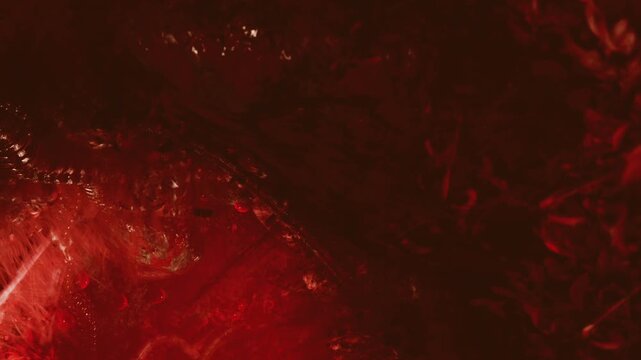 Swirling patterns and shades of deep red create an enchanting atmosphere. Light dances across the surface, revealing intricate textures and lively movement within this mesmerizing setting.