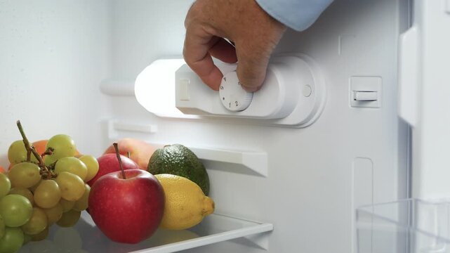Man Hand Open the Kitchen Fridge Door and Set the Thermostat. Making the Fridge Temperature Control for Optimum Function.