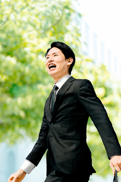 オフィス街を元気に歩く男性ビジネスマン