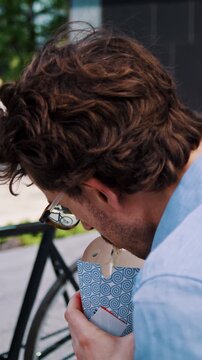 Man pauses with takeaway box near bicycle on office steps