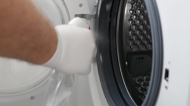 Man Doing Periodic Maintenance, Cleaning the Washing Machine. A Housekeeper Washing and Cleaning a Laundry Machine.
