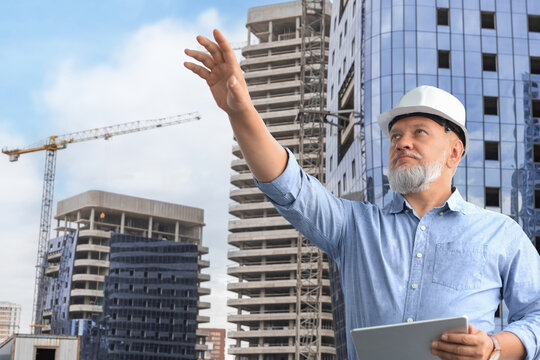 Mature architect wearing hardhat inspecting new building.