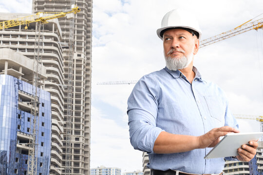 Mature architect wearing hardhat inspecting new building.