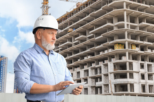 Mature architect wearing hardhat inspecting new building.