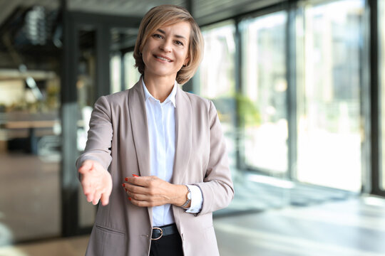 Business woman with an open hand ready for handshake in office.