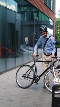 Man retrieves bicycle from parking rack in modern office passage