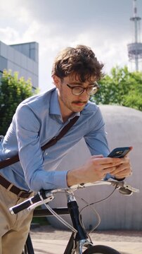 Man waits holding smartphone near bicycle and white sculpture