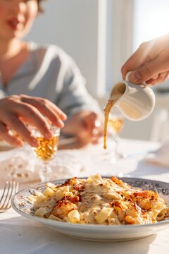 Pappardelle pasta with grilled shrimp and creamy bisque sauce being poured from a white jug, served on a blue transferware plate for a dinner menu
