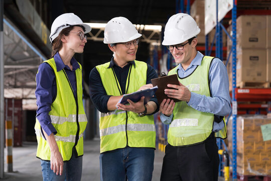 Workers, warehouse storage and logistics. Diverse group of warehouse workers wearing safety hard hats discussing inventory management and operations logistics planning in industrial storage warehouse