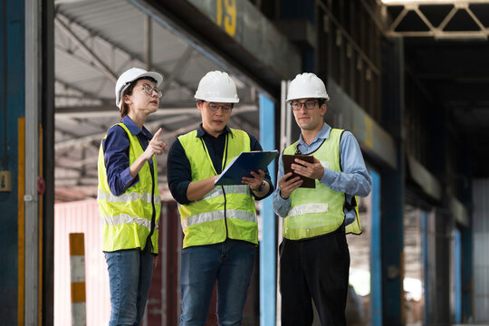 Workers, warehouse storage and logistics. Diverse group of warehouse workers wearing safety hard hats discussing inventory management and operations logistics planning in industrial storage warehouse