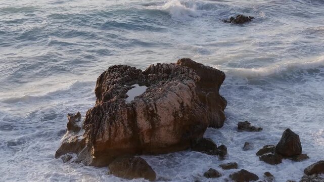 Rugged Seaside Rocks Surrounded by Foamy Ocean Waves at Sunset 