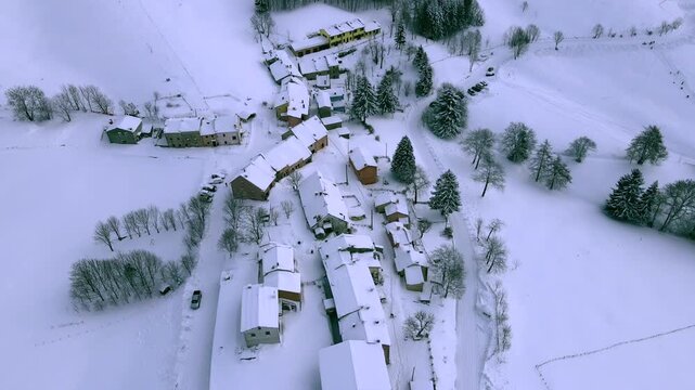 Aerial drone 360 degree orbit over small snow-covered mountain village, Pagani, Campofontana, Lessinia, Italy