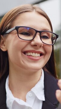 Close-up portrait of a young woman smiling with joy as she looks at her smartphone screen, reacting happily to something she sees on her phone. Slow motion