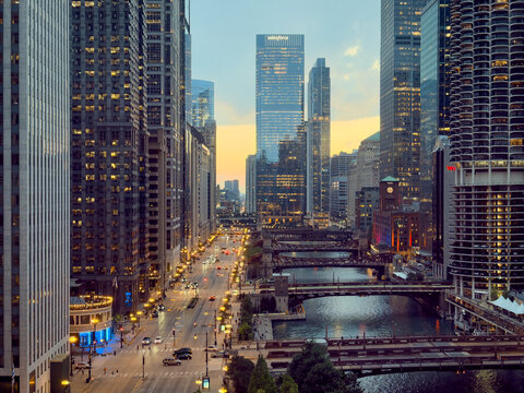 CHICAGO, IL, JUN 17, 2026: Elevated dusk view along the Chicago River, with Salesforce Tower, Marina City, lit bridges, a clock tower, a busy street and a glowing yellow sky