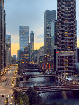CHICAGO, IL, JUN 17, 2026: Vertical twilight view of the Chicago River, with Marina City rising at right, Salesforce Tower at left, lit bridges, tree-lined riverbank and a streetlit avenue