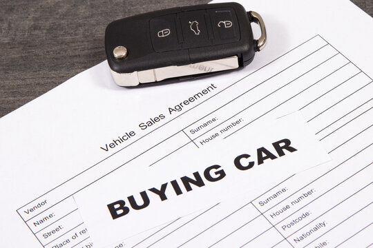 Car key, inscription buying car and vehicle sales agreement. Sales, purchases of automobile. Transportation