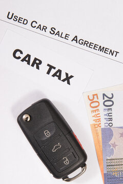 Car key, euro banknotes, inscription car tax and vehicle sales agreement. Sales, purchases, taxation of automobile. Transportation