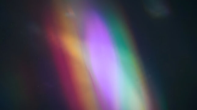 Abstract iridescent light streaks in vivid rainbow hues of purple, green, orange and red sweeping diagonally across a dark background, creating a dreamy blurred bokeh effect ideal for creative