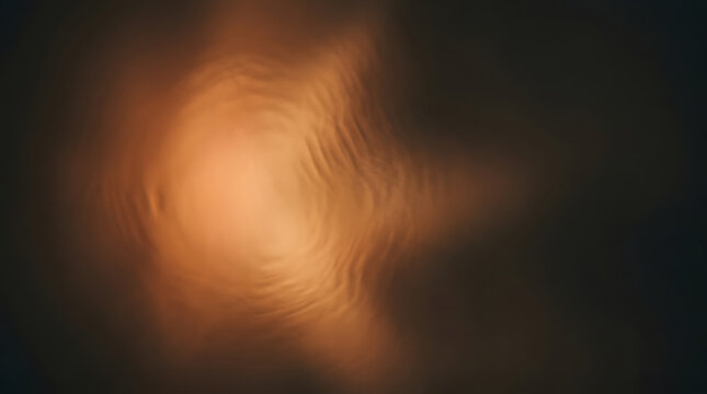 Abstract warm amber light glowing softly through rippling translucent fabric in dark moody setting with smooth flowing texture and golden orange tones creating an elegant atmospheric backdrop