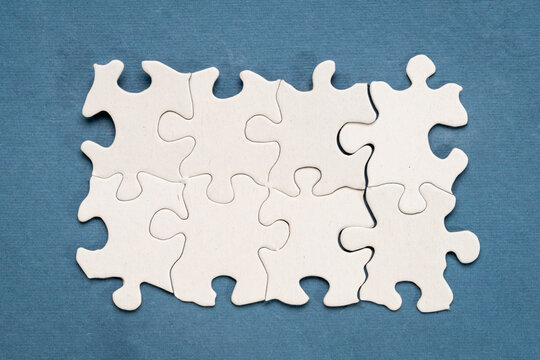 top view of white blank paper jigsaw puzzle on blue background, completing a task or solving a problem concept