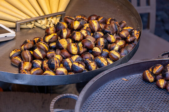 Roasted chestnuts on a street vendor's metal pan with paper cones in Rome, Italy