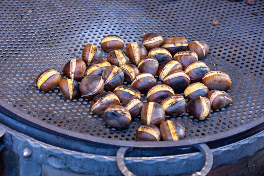 Roasted chestnuts on a perforated metal pan at a street stall in Rome, Italy, autumn food