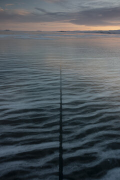View of a long crack in the frozen ice of Lake Baikal under a soft sunset sky, Russia.