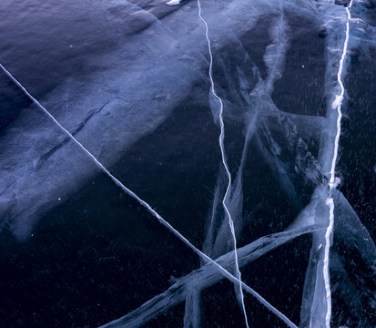 View of the deep blue frozen surface of Lake Baikal with intricate white cracks and winter ice textures in Russia.