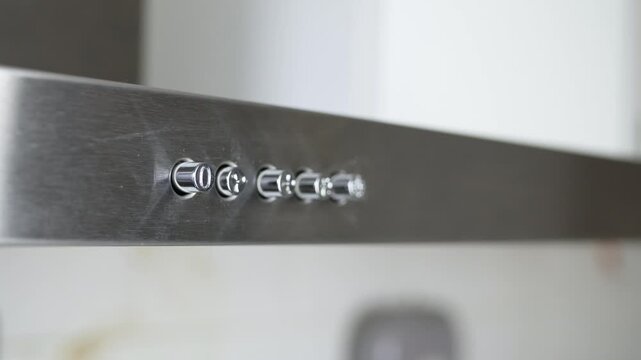 Finger Pressing Kitchen Range Hood Power Button Closeup. Man Pressing Stainless Steel Range Hood Switch Detail.