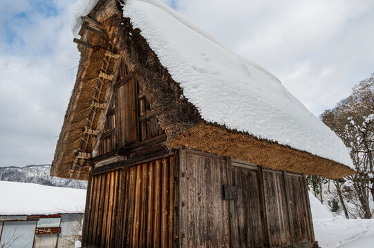 Traditional thatched roof wooden house covered in snow