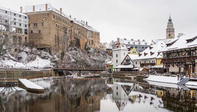 View of Cesky Krumlov Castle overlooking the Vltava River with snow-covered rooftops and historic buildings in Cesky Krumlov, South Bohemian Region, Czechia.
