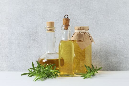 Rosemary oil with green rosemary sprig, aromatic oil for cooking. Homemade rosemary oil, natural cooking seasoning. Organic spiced oil on glass bottles. Healthy cooking.