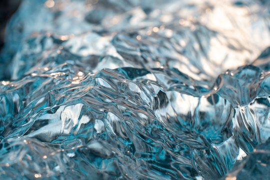 View of translucent glacial ice with textured surfaces and blue tones reflecting sunlight in Iceland.