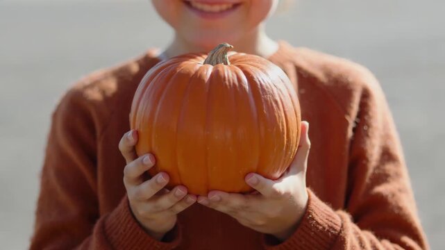 Captures Close Of Childs Torso Hands Holding Pumpkin Child Wearing Textured Rust Colored Sweater With Tag On Left Sleeve Indicating New Recently Purchased