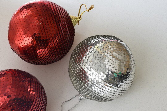 Top view of red and silver sequin Christmas baubles with sparkling glitter details, festive holiday decorations, elegant seasonal background, and shimmering metallic textures.