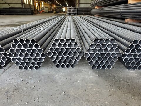 Rows of bundled black steel pipe receding through a warehouse