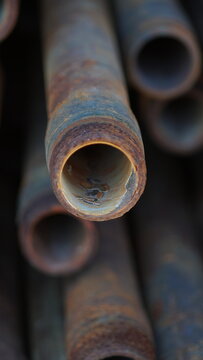 Rusty threaded steel pipe end in a stack with soft background