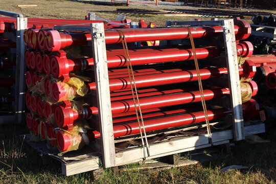 Red steel pipes packed in a wooden crate frame on a pallet