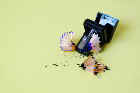 Black sharpener with shavings on color background.