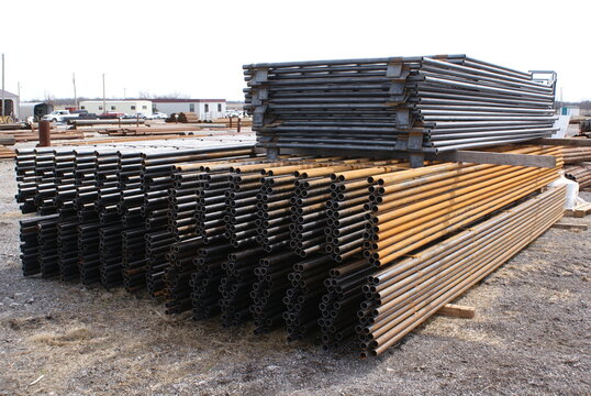Stacked steel pipe and livestock fence panels in a supply yard