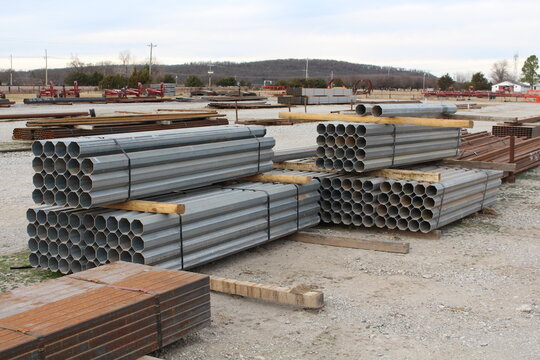 Stacks of galvanized octagonal steel pipe in an outdoor supply yard