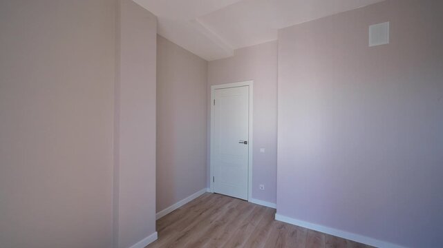 Spacious empty corner in apartment with light walls, wooden floor, white door, clean finish, minimalist interior, neutral palette.
