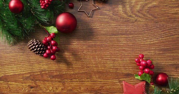 Showing left cluster resting on wood table, with green sprigs baubles pinecone berries, copy space
