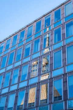View of the Mole Antonelliana reflected in the glass facade of a modern building in Turin, Piedmont, Italy.
