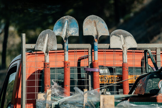 View of four shovels secured on the back of a utility truck with the Massif de l'Esterel in the background in Frejus, Provence-Alpes-Cote d'Azur, France.