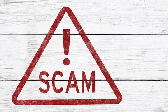 Red distressed Scam Alert stamp on weathered wood for warning