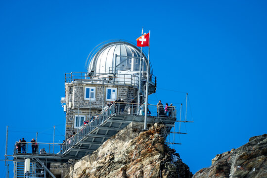 View of the Jungfraujoch Sphinx Observatory with its metallic dome, stone walls, and observation deck filled with people in Grindelwald, Wallis, Switzerland.