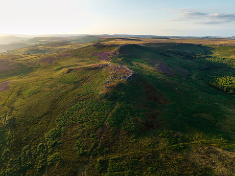 Beautiful drone landscape image view over Burbage South Edge in Peak District during Summer heather sunset