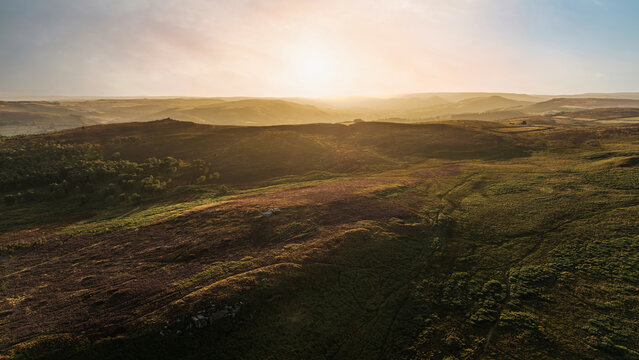 Beautiful drone landscape image view over Burbage South Edge in Peak District during Summer heather sunset