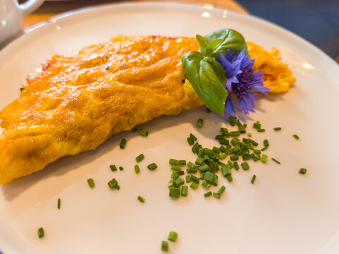 Toblach, Italy. Golden Omelette Garnished with Fresh Basil, Chives and Edible Blue Flower